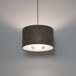 Lampa wisząca Lago S w kolorze szarym z kloszem w kształcie cylindrycznym, zawieszona na cienkim przewodzie. Wnętrze klosza białe, widoczna żarówka E27, emitująca ciepłe światło, na tle gładkiej, jasnej ściany.