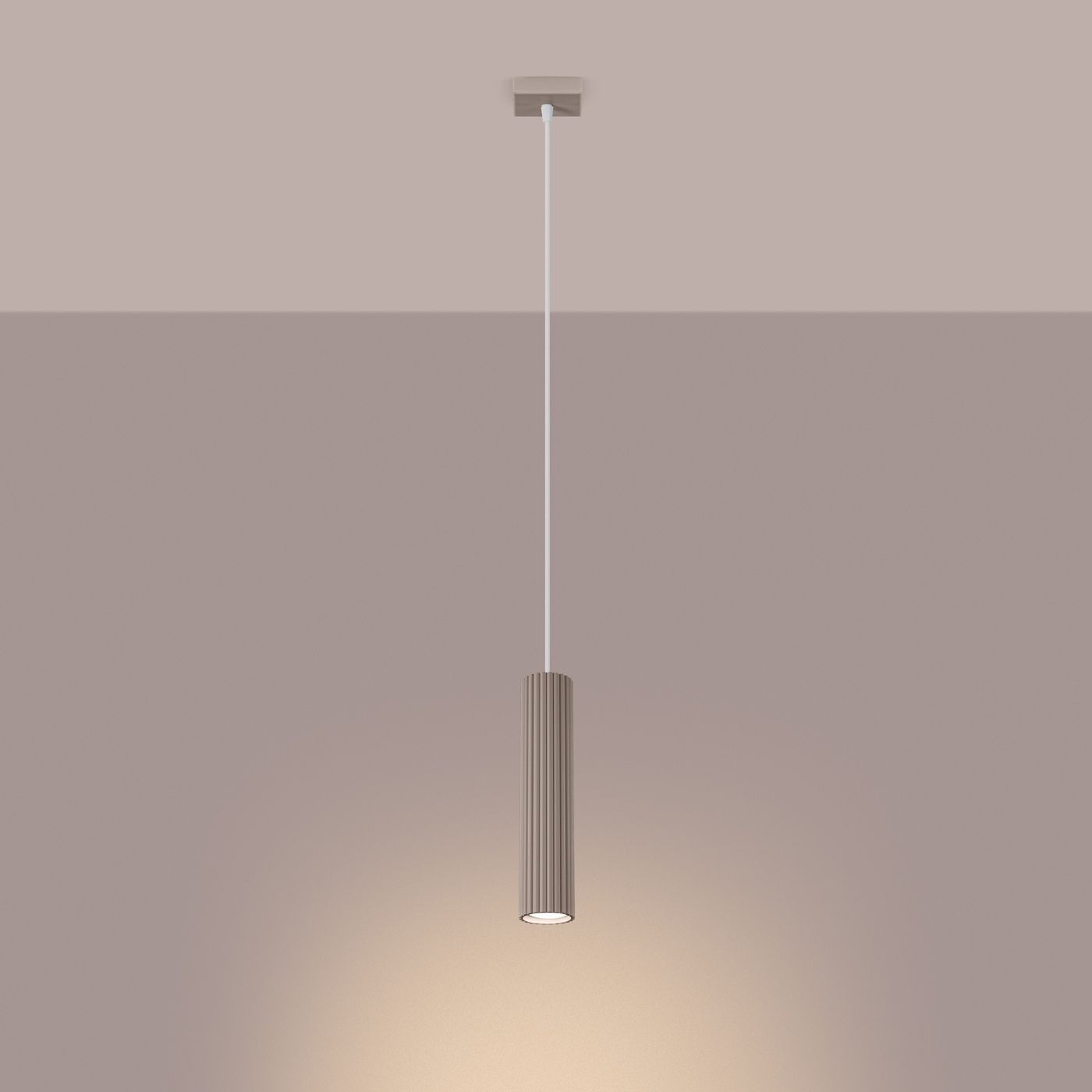 Lampa wisząca Karbon 1 lampa 1xGU10 w kolorze taupe, o cylindrycznym kształcie z pionowymi żłobieniami. Zawieszona na cienkim przewodzie, emitująca światło w dół. Prosta konstrukcja w nowoczesnym stylu, umieszczona na jednolitym, jasnym tle.