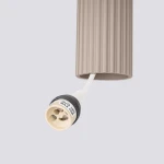 Lampa wisząca Karbon 3P w kolorze taupe z trzymaczem na trzy żarówki GU10. Widoczny fragment obejmy z teksturowanym wykończeniem oraz gniazdo żarówki z oznaczeniem maksymalnej mocy 10W. Kąt ujęcia z dołu.