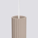 Lampa wisząca Karbon 3P w kolorze taupe, z trzema miejscami na żarówki GU10. Posiada cylindryczny, żłobkowany klosz z białym przewodem zawieszenia, widoczna górna część klosza w zbliżeniu.