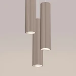 Lampa wisząca Karbon 3P w kolorze taupe z trzema cylindrycznymi kloszami z rowkowaną fakturą. Klosze mają otwarte spodnie części, montowane na cienkich przewodach, zawieszone w poziomie na jasnym tle.