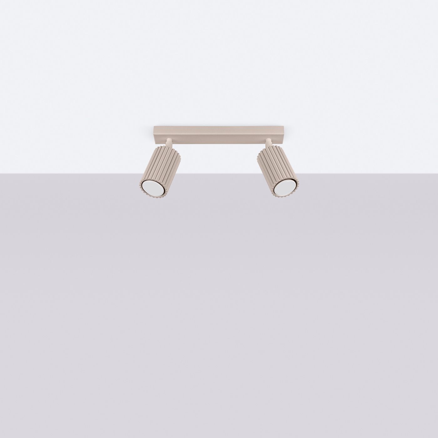 Lampa sufitowa Karbon w kolorze taupe z dwoma reflektorami GU10. Ujęcie frontalne, produkt zamontowany na suficie. Reflektory mają teksturowany, żłobkowany kształt, a ich dolne części są okrągłe i białe. Tło jasne, jednolite.