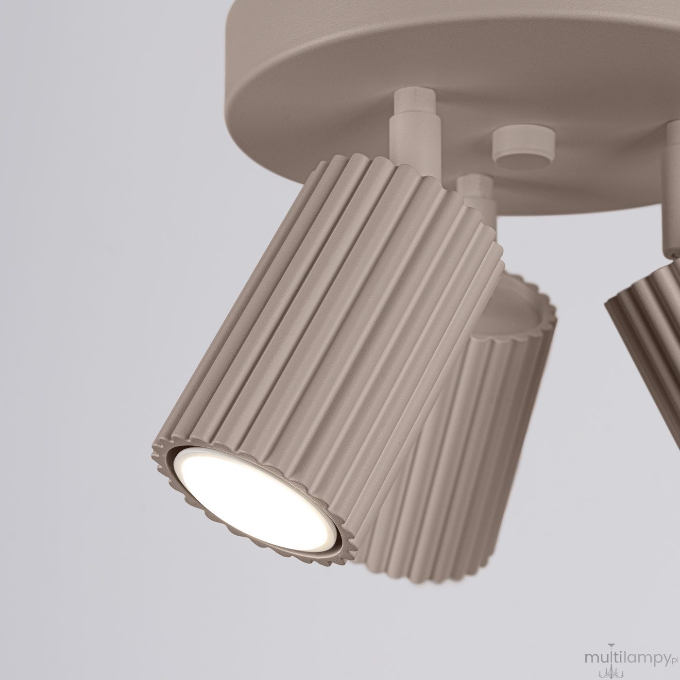 Lampa sufitowa Karbon z trzema reflektorami GU10 w kolorze taupe. Ujęcie z bliska, pokazujące fakturowane klosze o pionowych żłobieniach. Klosze skierowane w dół, montowane na okrągłej podstawie.