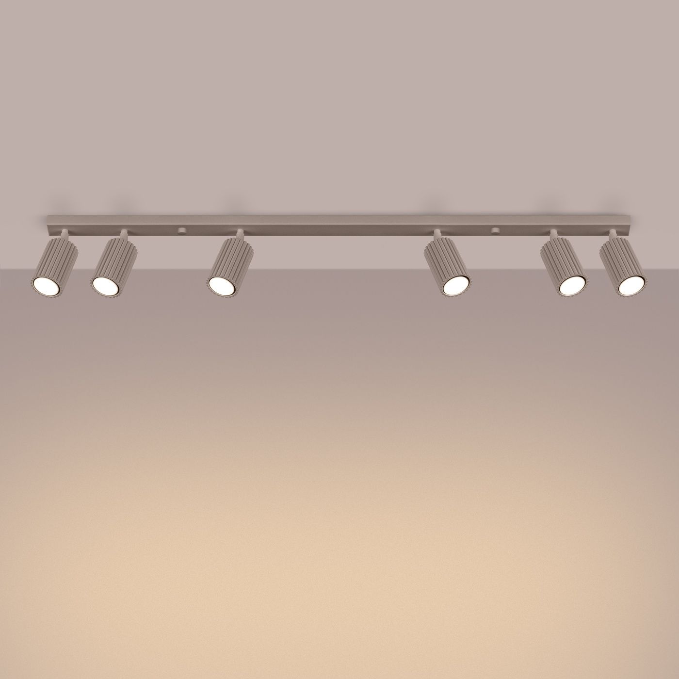 Lampa sufitowa Karbon w kolorze taupe, z sześcioma ruchomymi reflektorami GU10, zamocowana na prostokątnej szynie. Reflektory mają teksturowaną powierzchnię i są ustawione w linii, skierowane w dół. Tło w odcieniu beżowym.