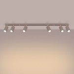 Lampa sufitowa Karbon w kolorze taupe, z sześcioma ruchomymi reflektorami GU10, zamocowana na prostokątnej szynie. Reflektory mają teksturowaną powierzchnię i są ustawione w linii, skierowane w dół. Tło w odcieniu beżowym.