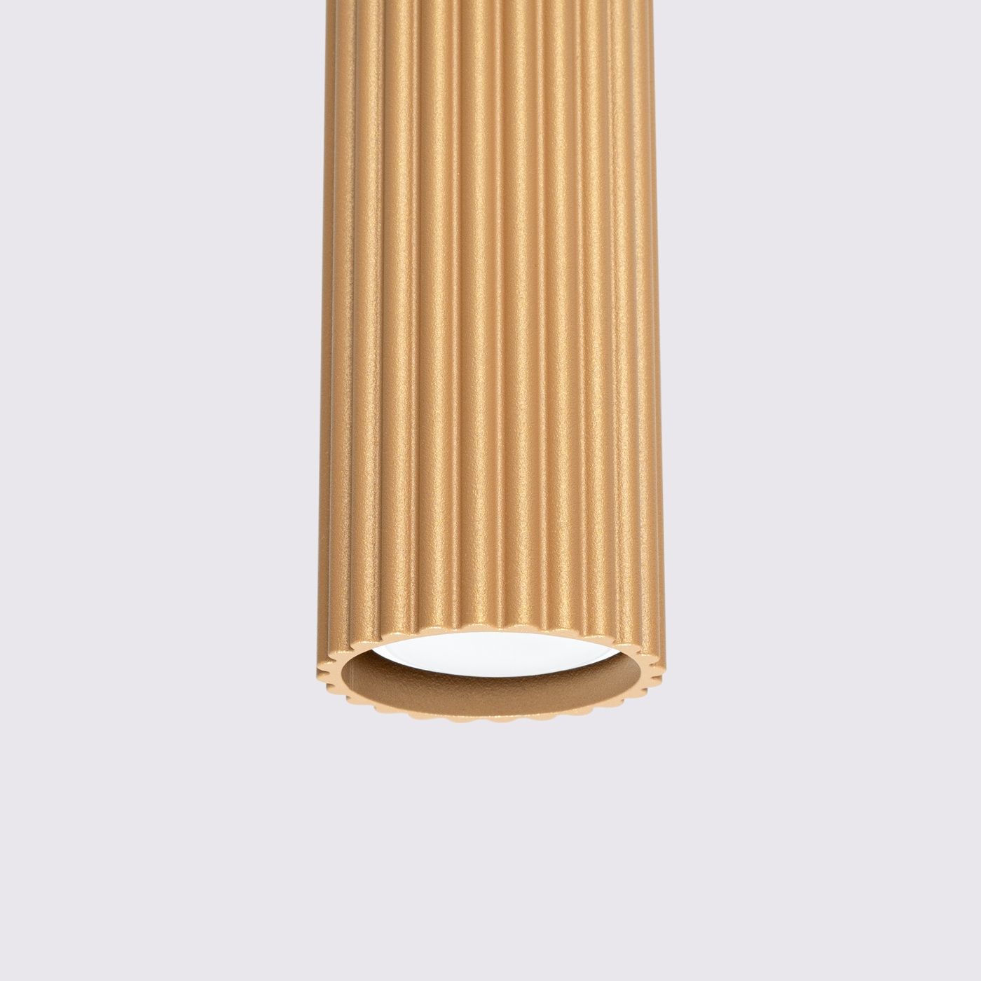 Lampa wisząca Karbon w kolorze złotym z oprawą GU10, o cylindrycznym kształcie z fakturą w pionowe żłobienia. Zawieszona pionowo, z widocznym wnętrzem, idealna do nowoczesnych wnętrz. Tło proste, w jasnym odcieniu.