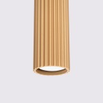 Lampa wisząca Karbon w kolorze złotym z oprawą GU10, o cylindrycznym kształcie z fakturą w pionowe żłobienia. Zawieszona pionowo, z widocznym wnętrzem, idealna do nowoczesnych wnętrz. Tło proste, w jasnym odcieniu.