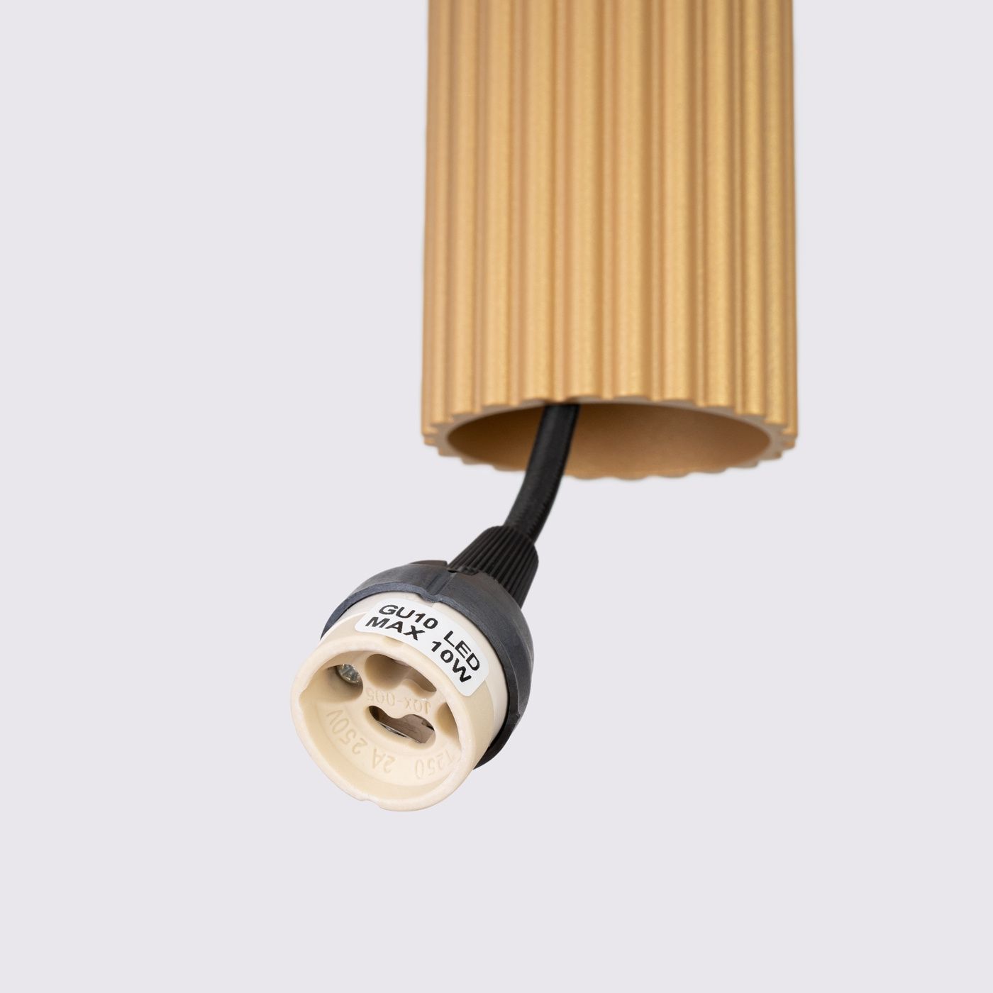 Lampa wisząca Karbon 1 z oprawą w kolorze złotym, z fakturą w poziome rowki. Widoczny gwint GU10 do żarówki LED (maks. 10W) oraz czarny przewód zasilający. Ujęcie z dołu, pokazujące detal mocowania.