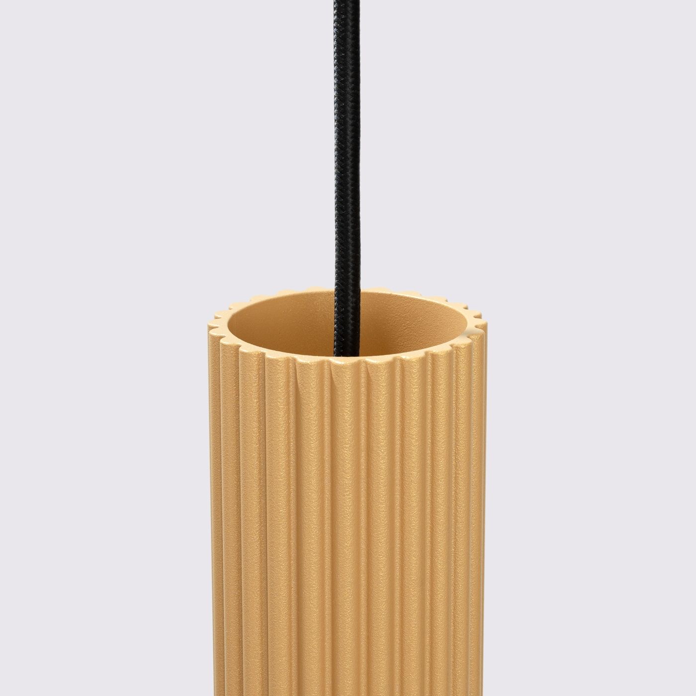 Lampa wisząca Karbon 3 w kolorze złotym, z trzema oprawami GU10. Posiada cylindryczny klosz z rowkowaną fakturą i czarnym kablem. Ujęcie z góry, ukazujące detale klosza.