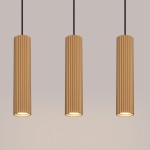 Lampa wisząca Karbon 3 w kolorze złotym, z trzema cylindrycznymi kloszami z rowkowanej powierzchni, zawieszona na czarnych przewodach. Klosze mają otwarte dolne części, co umożliwia montaż żarówek GU10. Tło w jednolitym, jasnym odcieniu.