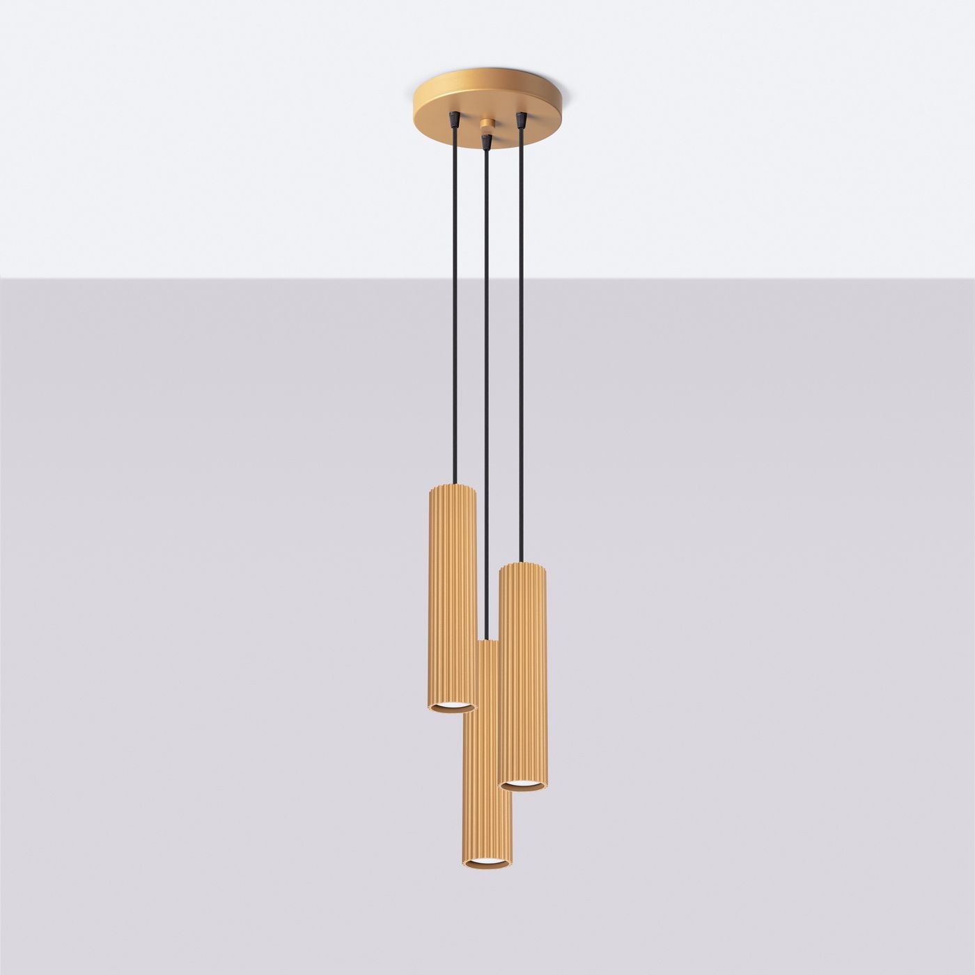 Lampa wisząca Karbon 3P w kolorze złotym, z trzema cylindrycznymi kloszami o fakturze żłobkowanej, zawieszona na czarnych linkach. Klosze montowane na okrągłej podstawie sufitowej. Idealna do nowoczesnych wnętrz.