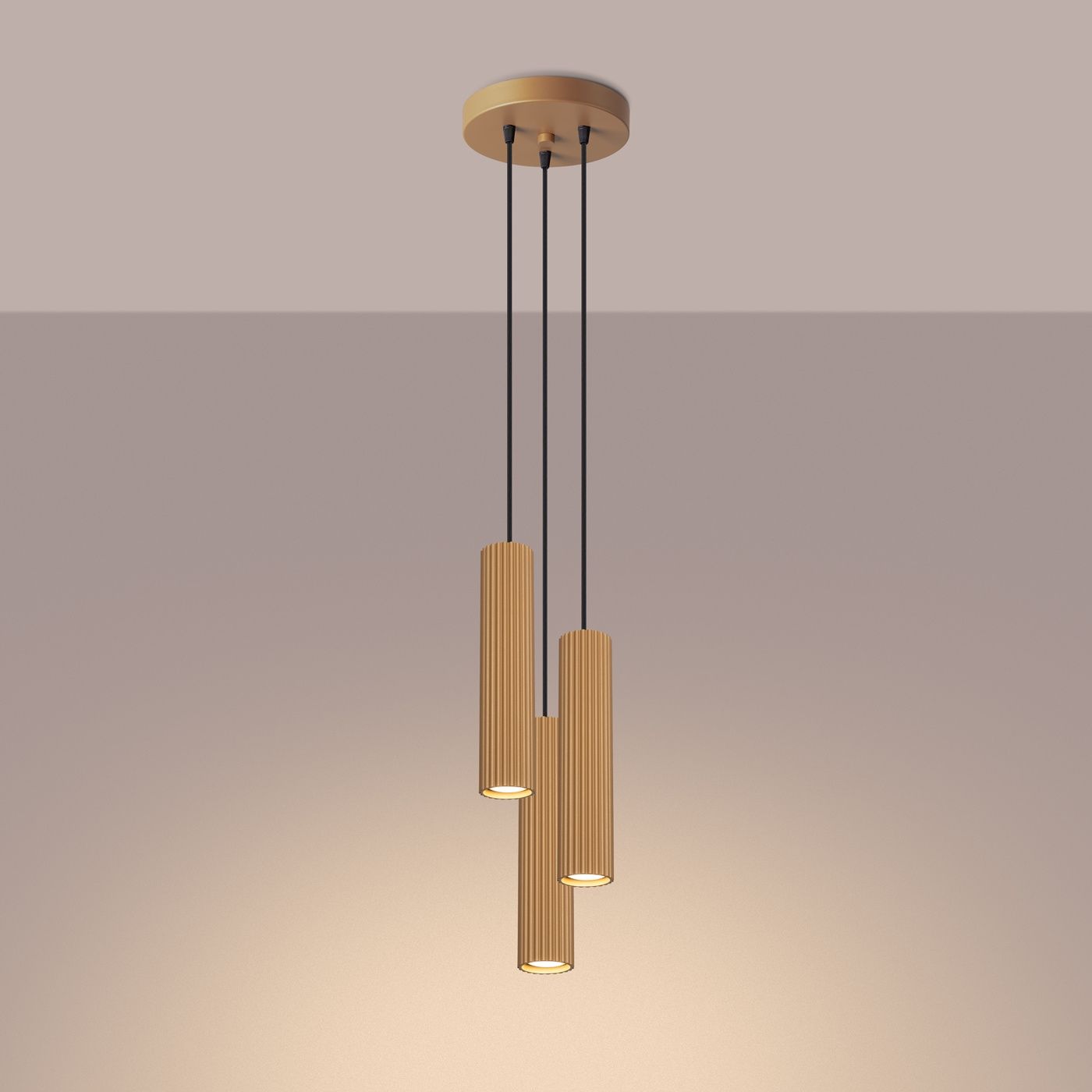 Lampa wisząca Karbon 3P w kolorze złotym z trzema cylindrycznymi kloszami o żebrowanej fakturze, zawieszona na czarnych linkach. Produkt montowany do sufitu, w minimalistycznym stylu, idealny do nowoczesnych wnętrz.