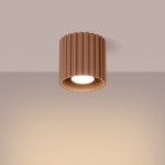 Lampa sufitowa Aura 1xGU10 w kolorze mocca, o cylindrycznym kształcie z falistym wzorem. Zawieszona pod sufitem, z widocznym źródłem światła w środku. Tło w odcieniu jasnoszarym, co podkreśla kolor lampy.