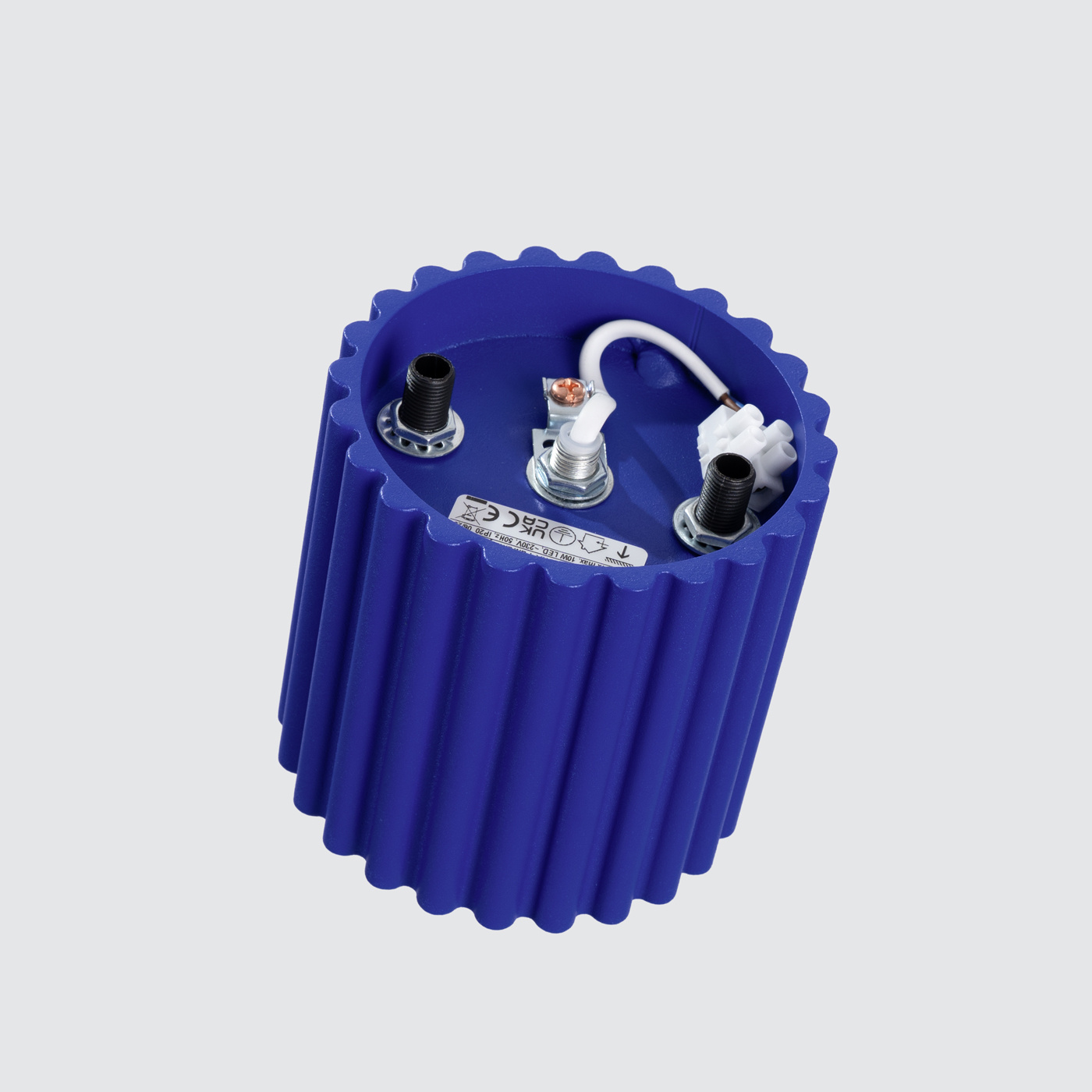 Lampa sufitowa Aura w kolorze ultramaryny z miejscem na żarówkę GU10. Widoczna jest okrągła, żłobiona obudowa oraz elementy montażowe. Ujęcie z góry, pokazujące wnętrze lampy i przewody elektryczne.