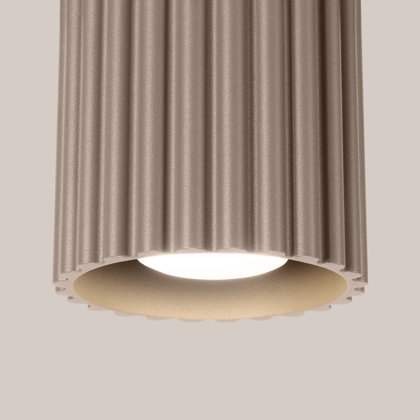 Lampa sufitowa Aura w kolorze taupe, z teksturowanym, żebrowanym kloszem. Ujęcie z bliska, pokazujące źródło światła GU10. Klosz ma okrągły kształt z gładkim wnętrzem, montowany do sufitu.