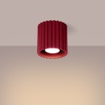 Lampa sufitowa Aura w kolorze burgundowym, z cylindrycznym kloszem o falistej teksturze. Ujęcie z dołu, pokazujące źródło światła GU10. Lampa zamontowana na gładkim, jasnym tle.