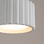 Lampa sufitowa Aura 1xGX53 w kolorze białym, z teksturowanym, falistym kloszem. Ujęcie z bliska na detal klosza, emitującego miękkie światło. Kształt cylindryczny z zaokrąglonymi krawędziami.