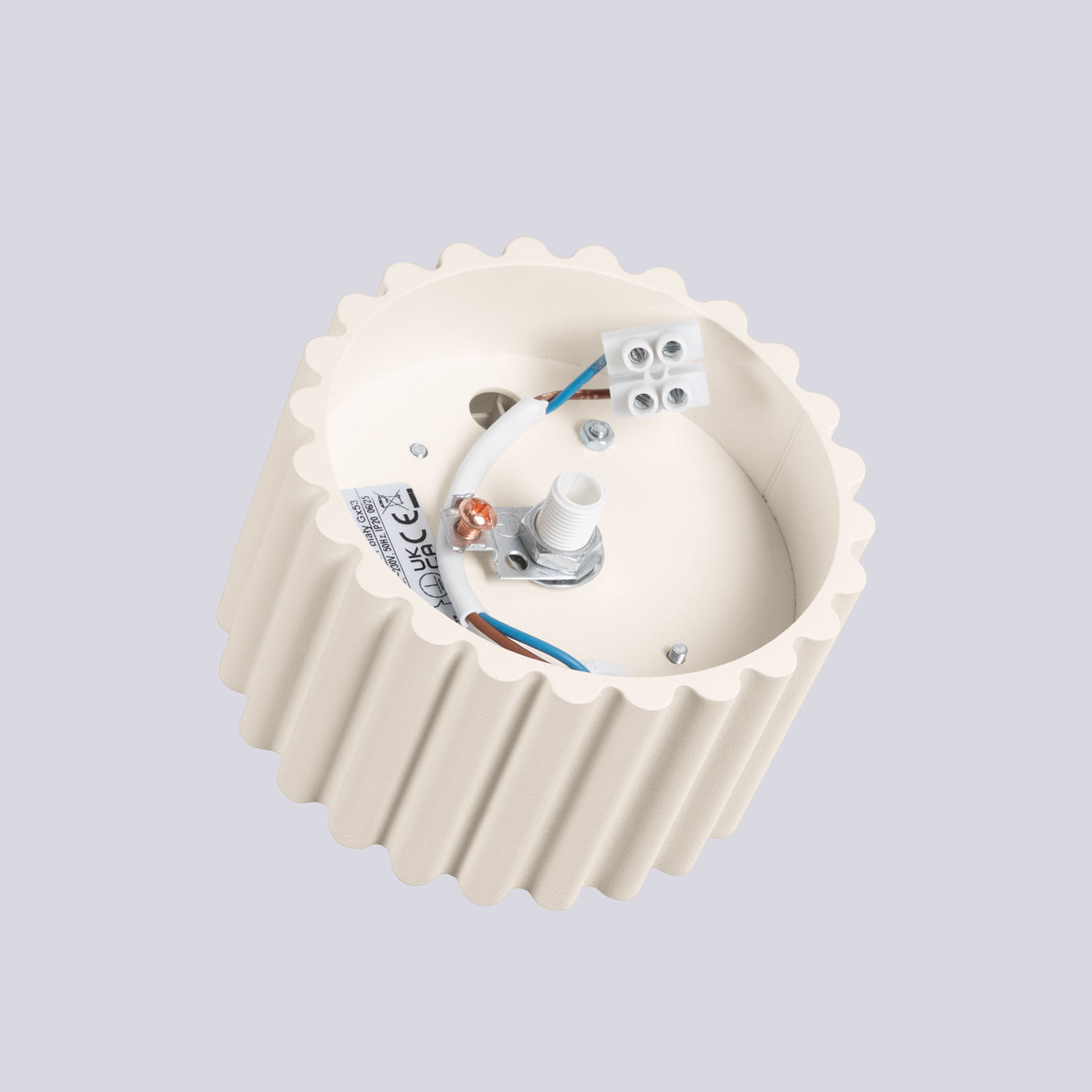 Beżowa lampa sufitowa Aura z gniazdem GX53, o okrągłym, falistym kształcie. Widoczna konstrukcja z elementami elektrycznymi, w tym złącza i przewody, umieszczona na jednolitym tle.