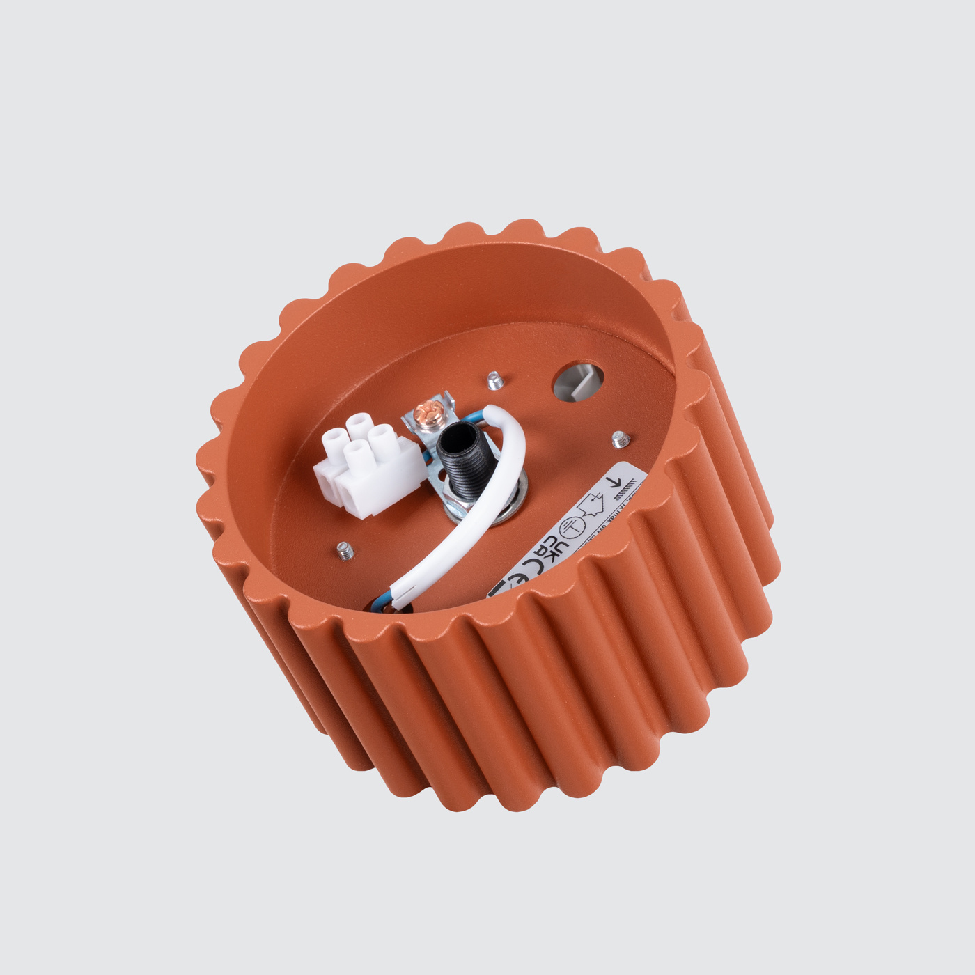 Lampa sufitowa Aura w kolorze ochra czerwona, z teksturowanym, cylindrycznym kloszem. Widok z góry, pokazujący wnętrze z miejscem na żarówkę GX53 oraz podłączeniami elektrycznymi. Klosz o falistej fakturze, montowany na suficie.