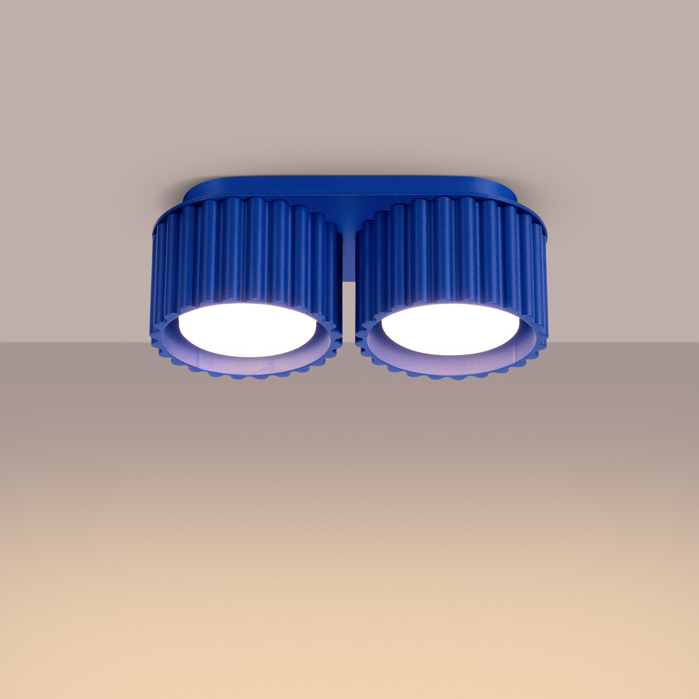 Lampa sufitowa Aura w kolorze ultramaryny z dwoma okrągłymi źródłami światła. Zainstalowana na prostokątnej podstawie, z żłobioną teksturą na obudowie. Ujęcie z dołu, ukazujące detale konstrukcji oraz jasne klosze.
