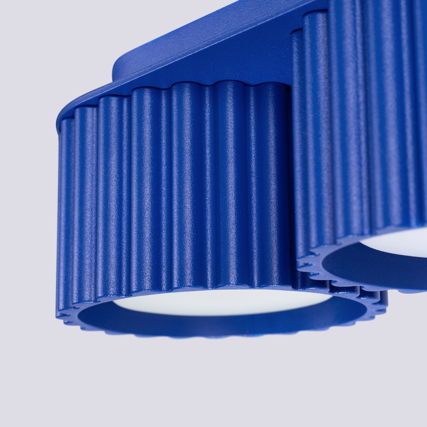 Lampa sufitowa Aura w kolorze ultramaryny z dwoma okrągłymi źródłami światła GX53. Widoczne żłobienia na metalowej obudowie oraz matowe klosze. Kąt ujęcia zbliżenie na detal, z góry, ukazujący strukturę i materiał.
