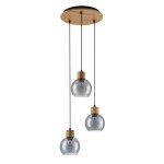 Lampa wisząca Velma z trzema szklanymi kloszami w kształcie kul, zawieszonymi na czarnych przewodach. Drewno w kolorze naturalnym stanowi górną osłonę. Klosze są przejrzyste, z metalowymi mocowaniami. Produkt wisi prosto z sufitu.