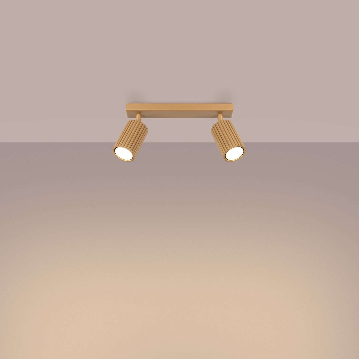 Złota lampa sufitowa Karbon, model SL.1561, z dwoma regulowanymi reflektorami GU10. Ujęcie frontalne, zamontowana na suficie, z widocznymi żłobieniami na korpusach lamp. Tło w odcieniach beżu, co podkreśla elegancki design.