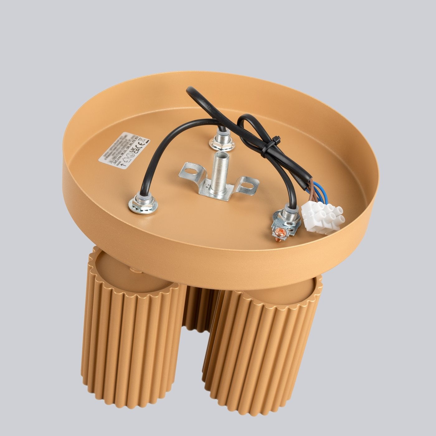 Lampa sufitowa Karbon w kolorze złotym, z trzema gniazdami GU10. Okrągła baza z metalowymi mocowaniami i przewodami, z widocznymi żebrowanymi elementami. Ujęcie z góry, ukazujące szczegóły konstrukcji oraz złącza elektryczne.