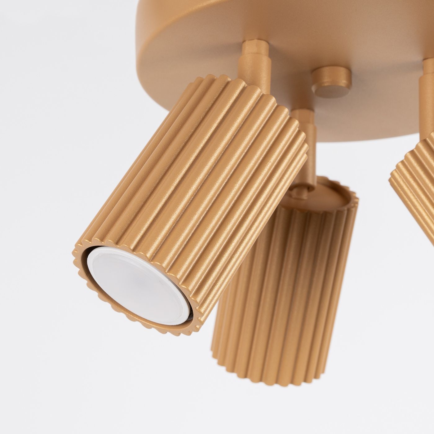 Złota lampa sufitowa (spot) Karbon z trzema reflektorami GU10. Reflektory mają teksturowaną, żłobkowaną powierzchnię i są zamocowane na okrągłej podstawie. Ujęcie z dołu, ukazujące szczegóły konstrukcji.