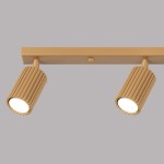 Złota lampa sufitowa Karbon L z czterema reflektorami GU10, o cylindrycznym kształcie z rowkowaną teksturą. Ujęcie z boku, ukazujące detale lampy na szarym tle. Lampa jest zamontowana na prostokątnej podstawie.
