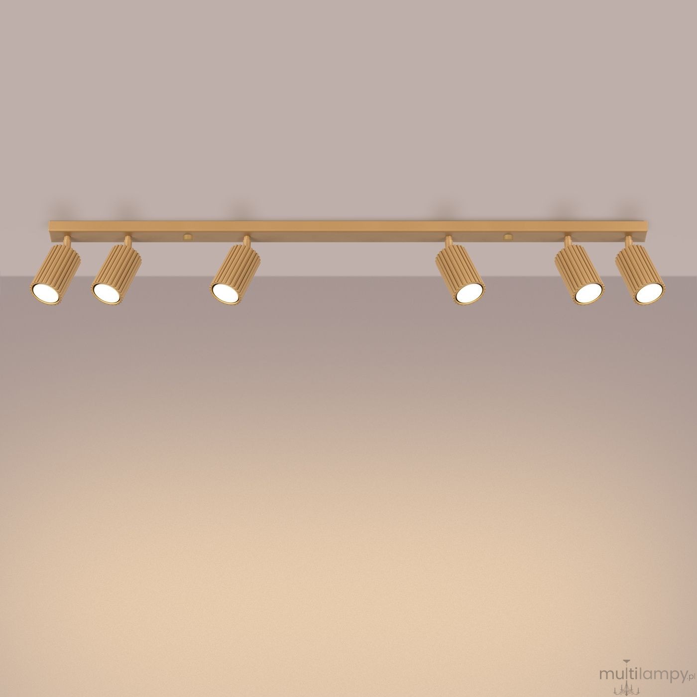 Złota lampa sufitowa typu spot z sześcioma regulowanymi oprawkami GU10. Oświetlenie zamontowane na prostokątnej belce, z wyraźnym, teksturowanym wykończeniem w kształcie cylindra. Kąt ujęcia frontalny, na jednolitym tle.