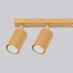 Lampa sufitowa Karbon 6xGU10 w złotym kolorze, z dwoma cylindrycznymi reflektorami o teksturowanej powierzchni. Reflektory są zamontowane na prostokątnej podstawie. Tło jest jasnoszare, co podkreśla elegancki design lampy.