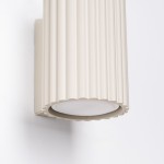 Kinkiet Karbon 10 w kolorze beżowym, z cylindrycznym kloszem o teksturowanej powierzchni, montowany na ścianie. Widoczny uchwyt z gładkiego materiału, z miejscem na żarówkę GU10. Ujęcie z boku, eksponujące detale i kształt.