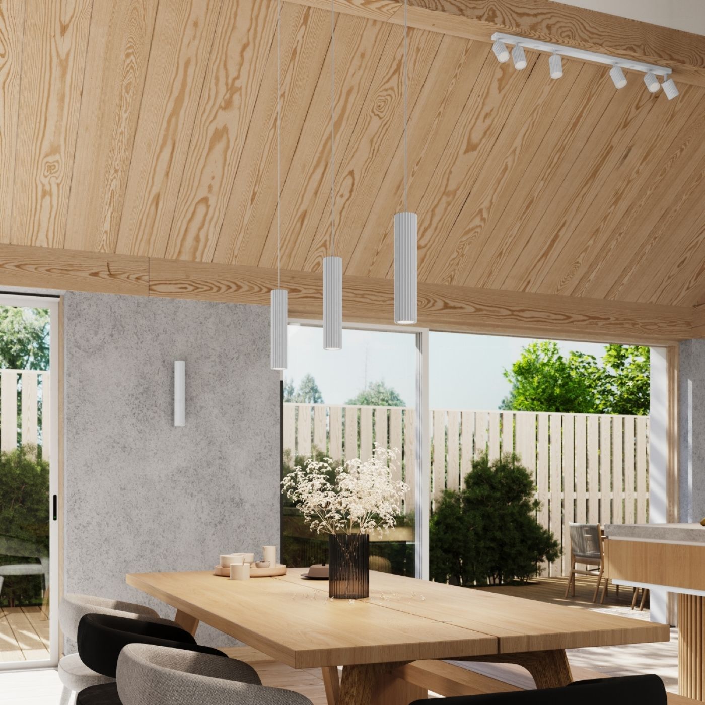 Kinkiet Karbon 20 w kolorze białym z dwoma gniazdami GU10, zamontowany na szarej ścianie. W tle widoczna drewniana sufit oraz stół z dekoracją i krzesłami, w aranżacji przestrzeni dziennej z oknem na ogród.