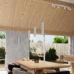 Kinkiet Karbon 20 w kolorze białym z dwoma gniazdami GU10, zamontowany na szarej ścianie. W tle widoczna drewniana sufit oraz stół z dekoracją i krzesłami, w aranżacji przestrzeni dziennej z oknem na ogród.