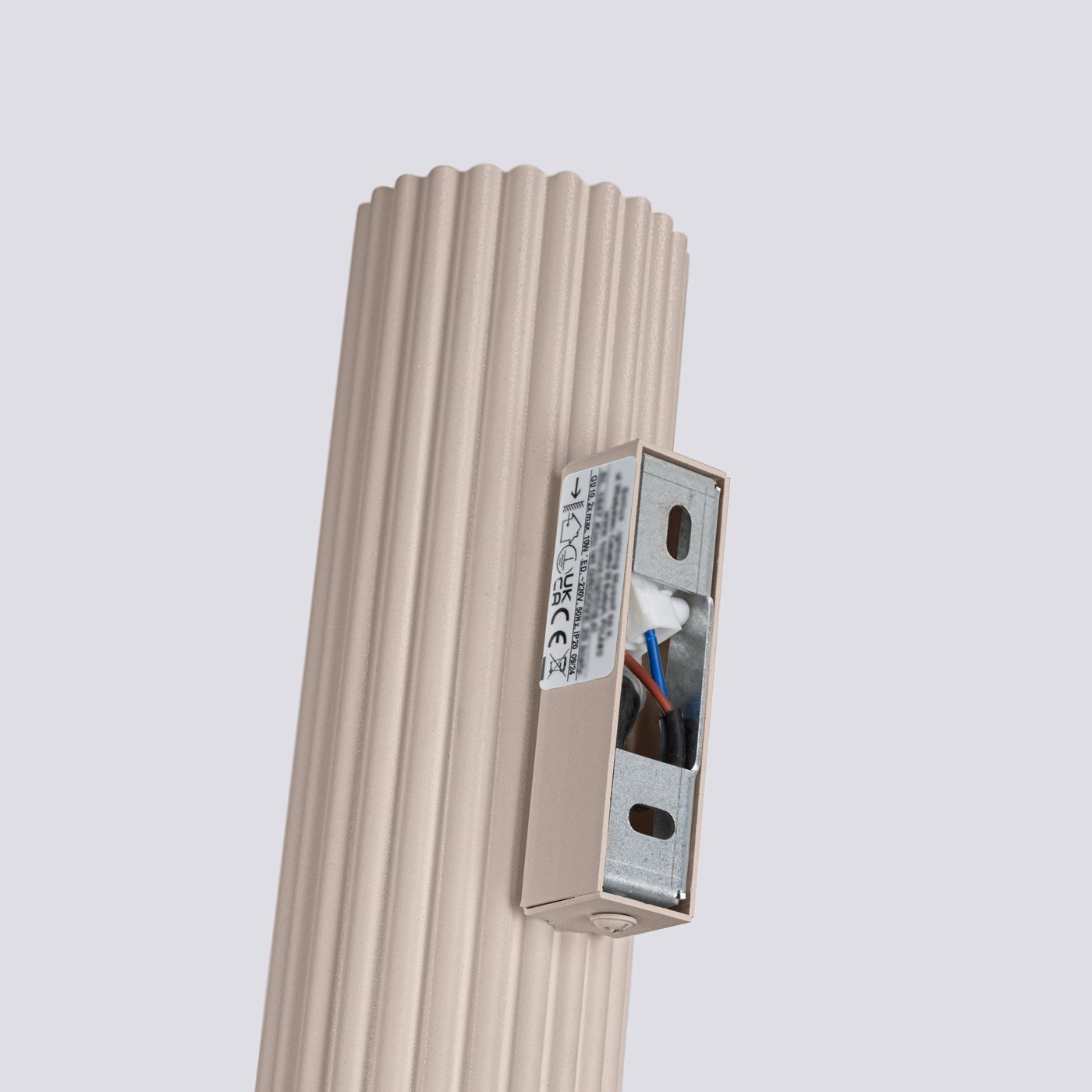 Kinkiet Karbon 20 w kolorze taupe, z dwoma gniazdami GU10. Ujęcie z boku pokazuje teksturowaną, żebrowaną obudowę oraz widoczny element mocujący z przewodami. Tło jasne, co podkreśla kolor lampy.