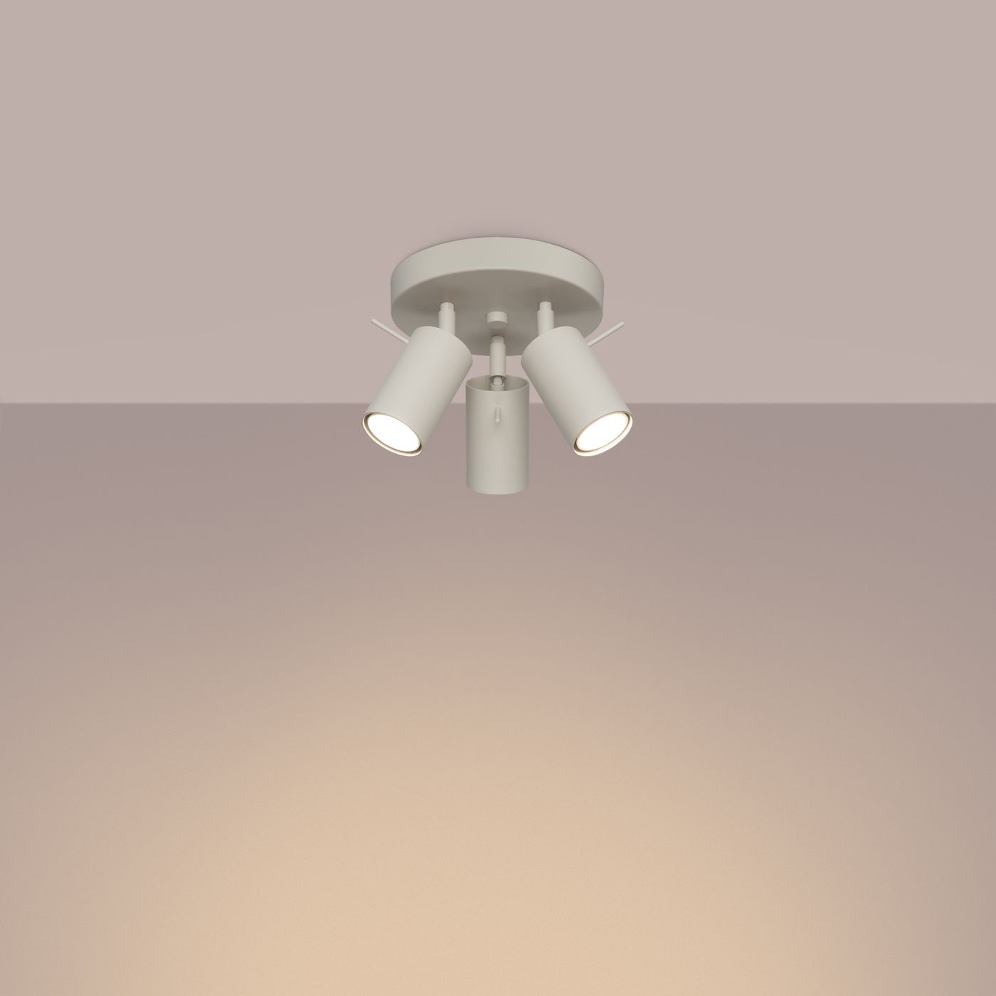 Beżowa lampa sufitowa typu spot z trzema oprawami na żarówki GU10, zamontowana na okrągłej podstawie. Ujęcie z dołu, ukazujące skierowane w różne strony klosze, na jednolitym tle.