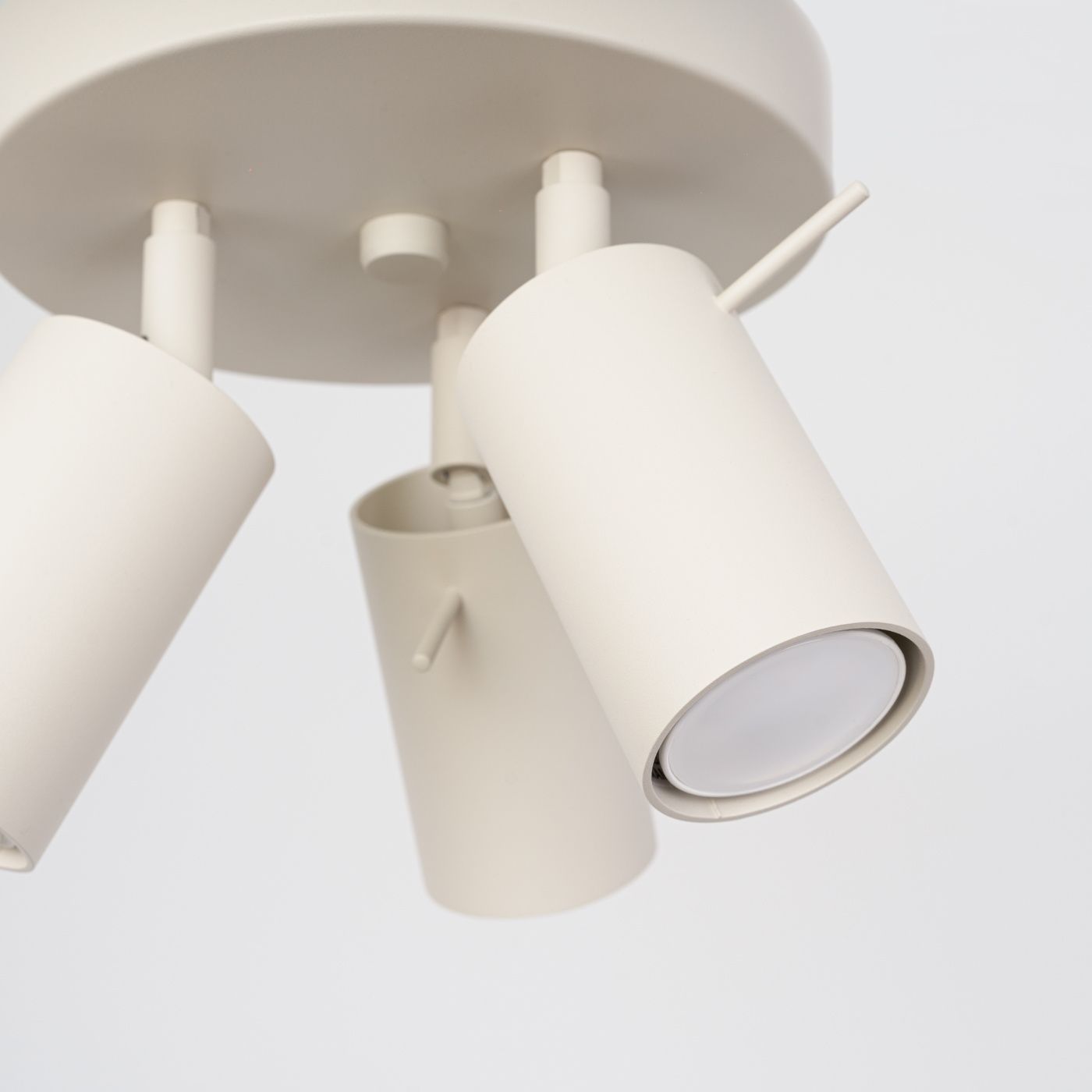 Beżowa lampa sufitowa Ring z trzema ruchomymi reflektorami GU10. Reflektory o cylindrycznym kształcie, zamontowane na okrągłej podstawie. Prosta konstrukcja, matowe wykończenie, idealna do nowoczesnych wnętrz.