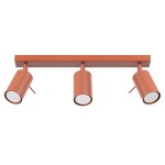 Lampa sufitowa typu spot w kolorze ochra czerwona, z trzema regulowanymi reflektorami GU10. Ułożona poziomo na prostokątnej podstawie, z widoczną metalową teksturą. Idealna do oświetlenia wnętrz.