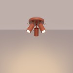 Lampa sufitowa typu spot w kolorze ochra czerwona, z trzema regulowanymi kloszami, zamontowana na okrągłej podstawie. Klosze mają cylindryczny kształt, a ich wnętrza są białe, co zapewnia efektywne oświetlenie.