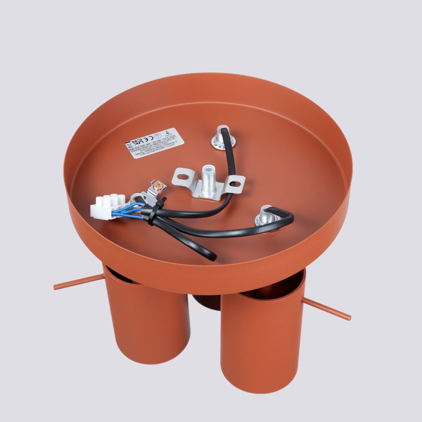 Lampa sufitowa Ring w kolorze ochra czerwona, z okrągłą podstawą i trzema gniazdami na żarówki GU10. Widoczne przewody i mocowania. Ujęcie z góry, pokazujące detale konstrukcji oraz połączenia elektryczne.