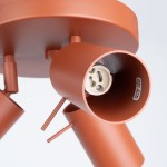 Lampa sufitowa Ring w kolorze ochra czerwona z trzema oprawami GU10. Widoczny detal uchwytów i gniazd. Kąt zbliżenia na jeden z reflektorów, ukazujący wewnętrzną część z oznaczeniem maksymalnej mocy 10W.
