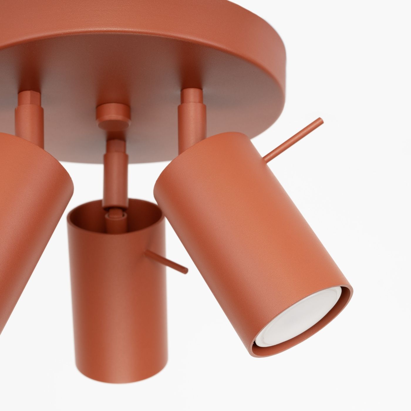 Lampa sufitowa Ring w kolorze ochra czerwona z trzema regulowanymi reflektorami GU10. Konstrukcja metalowa, cylindryczne klosze, zamontowana na okrągłej podstawie. Widok z dołu, ukazujący detale mocowania i kształt lampy.