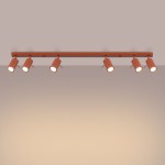 Lampa sufitowa Ring w kolorze ochra czerwona z sześcioma reflektorami GU10. Ujęcie frontalne, zamontowana na prostokątnej listwie, z lekko zaokrąglonymi kloszami skierowanymi w dół, na jednolitym tle.