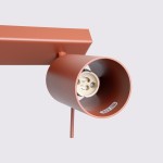 Lampa sufitowa typu spot w kolorze ochra czerwona, z metalowym kloszem o okrągłym kształcie, montowana na prostokątnej podstawie. Widoczne gniazdo na żarówkę GU10. Ujęcie z boku, ukazujące szczegóły konstrukcji.