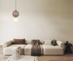 Lampa wisząca LED Pieve D25 o mocy 7W i temperaturze barwowej 3000K. Brązowa, z kulistym kloszem na górze i białą kulą na dole. Zawieszona w nowoczesnym wnętrzu nad sofy i stolikiem, na tle jasnej ściany.