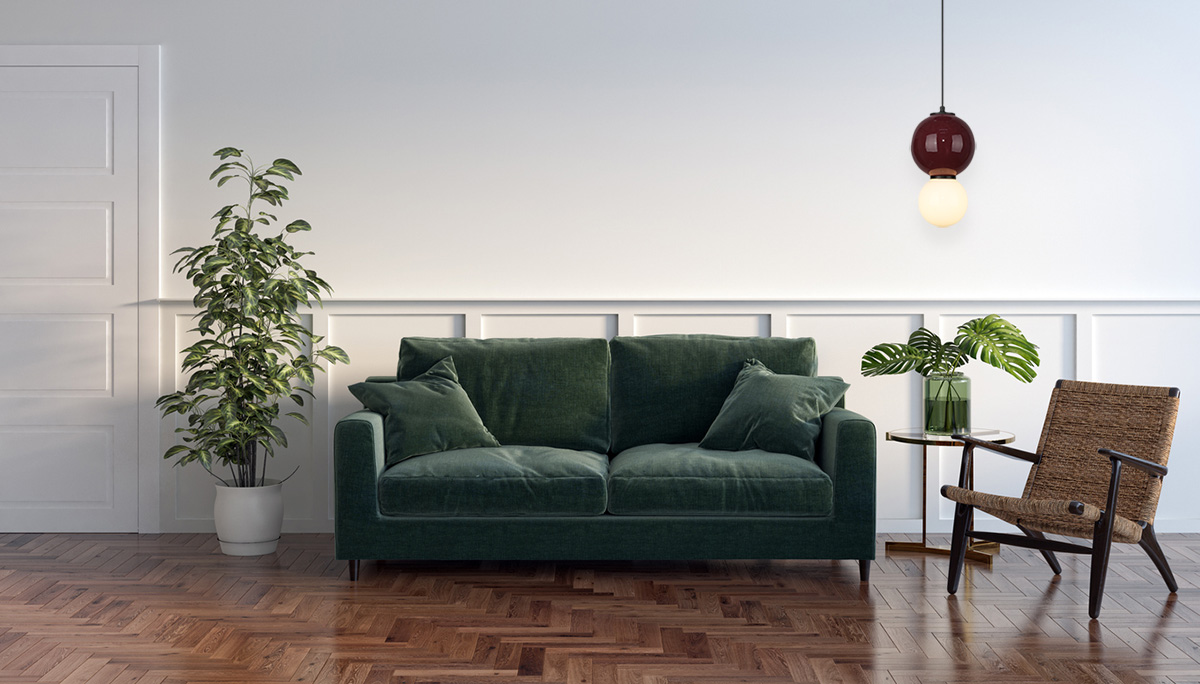 Lampa wisząca LED Pieve D25 o mocy 7W, w kolorze bordowym, z białym kloszem, zawieszona nad zielonym sofą. W tle widoczna biała ściana, rośliny oraz drewniana podłoga.