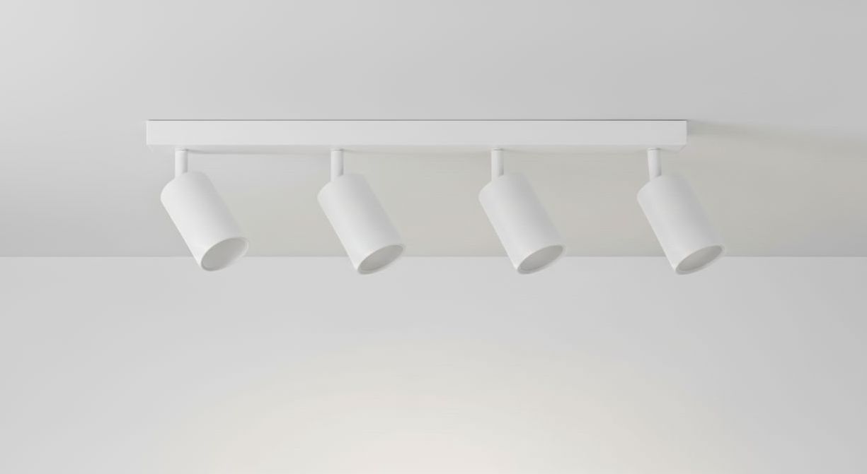 Biała lampa sufitowa 4-punktowa z prostokątnym stelażem, zawierająca cztery cylindryczne reflektory. Ujęcie frontalne, lampy skierowane w dół, na jednolitym tle. Idealna do oświetlenia wnętrz.