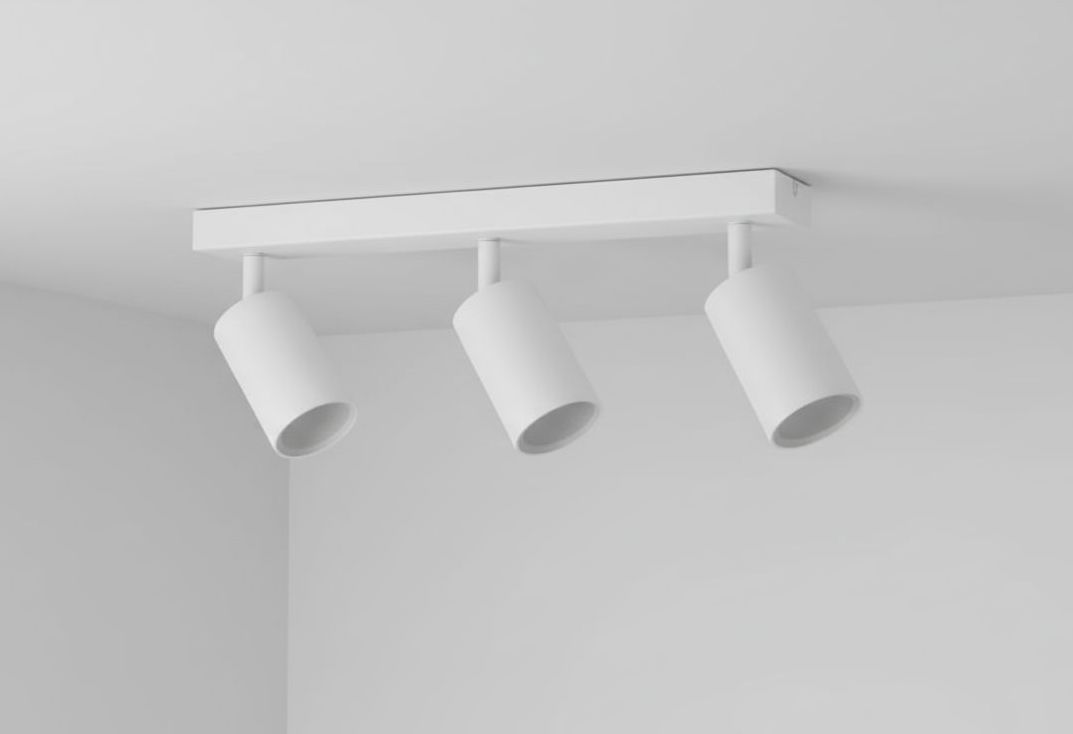 Lampa sufitowa Spoti 3-punktowa w kolorze białym, zamontowana na prostokątnej podstawie. Trzy cylindryczne reflektory skierowane w różnych kierunkach, zawieszone na krótkich wspornikach. Prosta forma, idealna do nowoczesnych wnętrz.