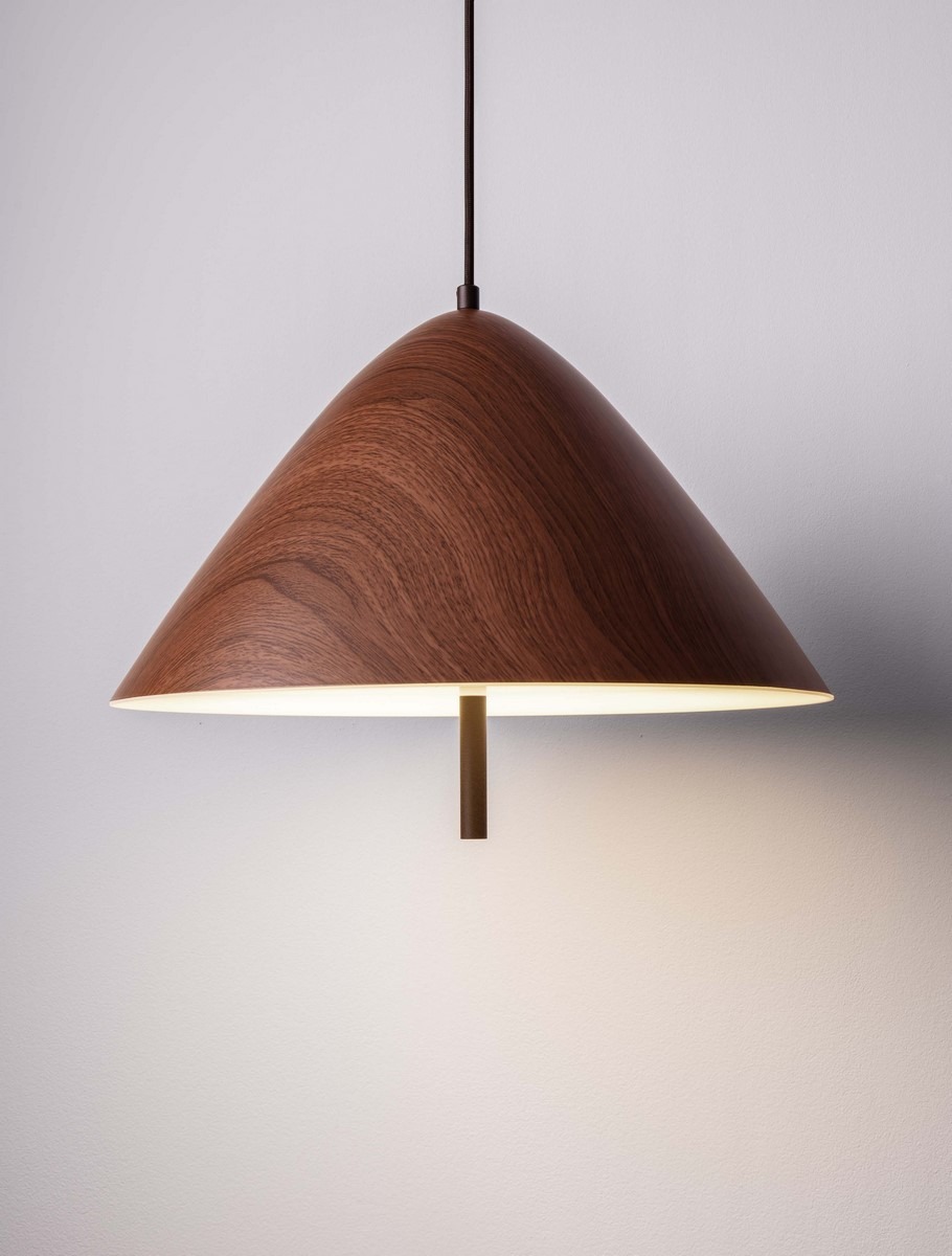 Lampa wisząca Carapari z kloszem w kształcie stożka, wykonana z ciemnego drewna, z wbudowanym źródłem LED 17W. Zawieszona na cienkim przewodzie, emituje ciepłe światło, idealna do nowoczesnych wnętrz. Tło jasne, minimalistyczne.